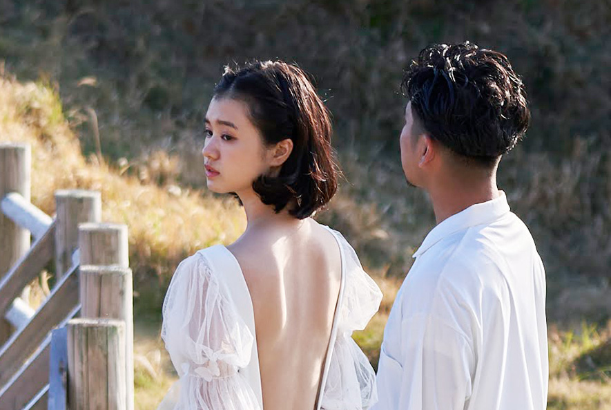 五島リトリート ray 灯台のふもとの草原で佇む新郎新婦