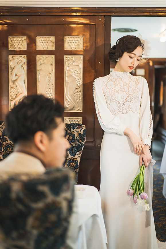 箱根リトリート オリエント急行室内で佇む新婦のそばで座っている新郎